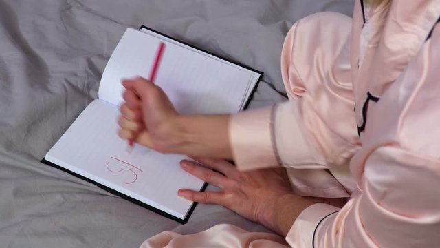 Woman writing stress word in red on notebook