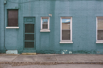 Green-blue brick building on empty sidewalk