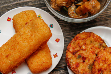 Crispy breaded fried fish fillet, vegetarian burger made from various type of vegetables and grilled champignons mushroom on old wooden table