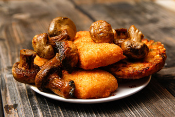 Crispy breaded fried fish fillet, vegetarian burger made from various type of vegetables and grilled champignons mushroom on old wooden table