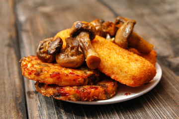 Crispy breaded fried fish fillet, vegetarian burger made from various type of vegetables and grilled champignons mushroom on old wooden table