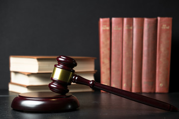 Judge gavel beside pile of books on wooden background
