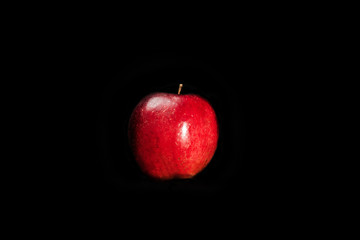 fresh red apple with droplets of water against black background with space for text
