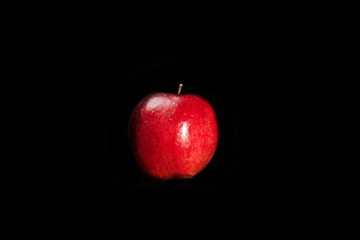 Fototapeta na wymiar fresh red apple with droplets of water against black background with space for text
