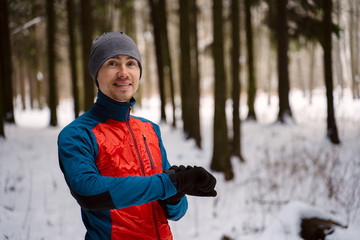 Runner wearing warm sporty clothes looks at a modern smart clock and counts up spent calories