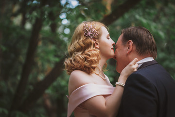 Fototapeta premium bride and groom kissing in the summer forest