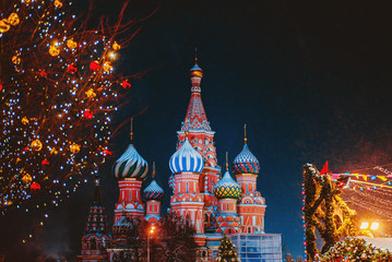 Obraz premium Saint Basil cathedral among new year festive decorations on Red Square in Moscow. Christmas fair in Russia at evening while snow falling.