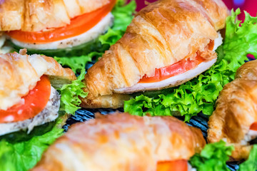 Close up fresh croissants with salad, ham and cheese on table