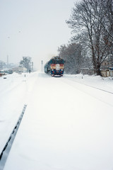 Train on the railway in heavy snow storm. Passenger train moves on the railway in winter in Ukraine.