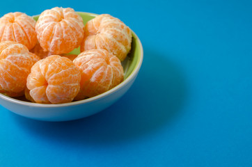 tangerines in a plate on a blue background close-up, copy space