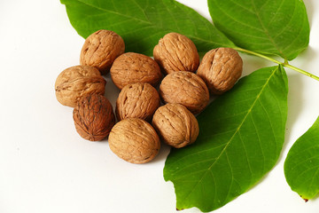 dry shelled walnut and green walnut leaves, on White background