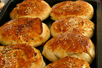 freshly baked buns with sesame seeds, raw dough for making donuts, with sesame seeds,