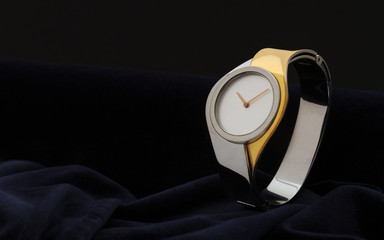 Modern woman gold and silver Wristwatch on dark velvet fabric background