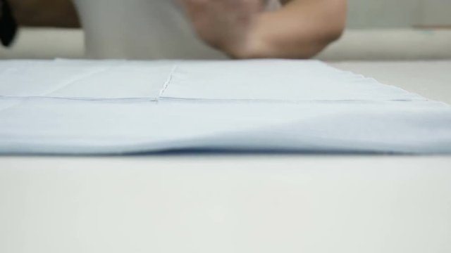 Cutting the fabric, sewing work. Cutting room, woman hands cutting blue cloth tailoring knife.