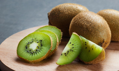 Fresh ripe sliced kiwi fruit, whole half and piece organic juicy kiwi fruits on wooden background
