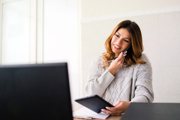 business woman working on her laptop and digital tablet while talking to the phone