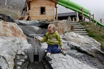 Child playing in a water circuit near the Swiss mountains.