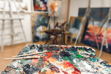 Palette of oil paints and brushes on the background of a studio. Background. Copyspace
