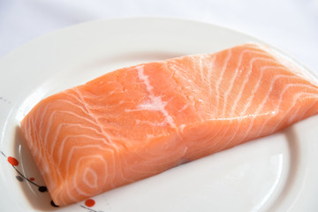 Salmon in white dish on white blackground.
