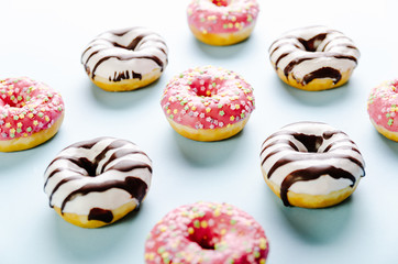Donut with pink icing and star sprinkles on the top on blue background. Selective focus.
