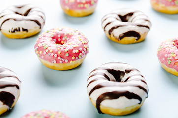 Donut with pink icing and star sprinkles on the top on blue background. Selective focus.