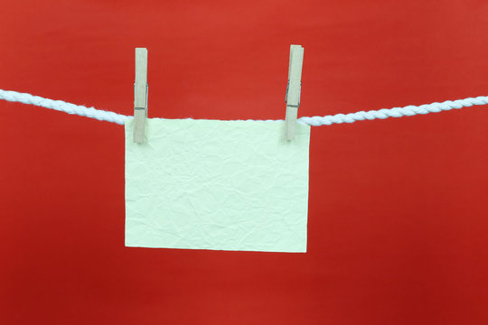 Empty note green paper hang on the clothesline and have copy space with red background.