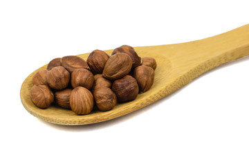 Brown wooden spoon with hazelnuts isolated on white background.
