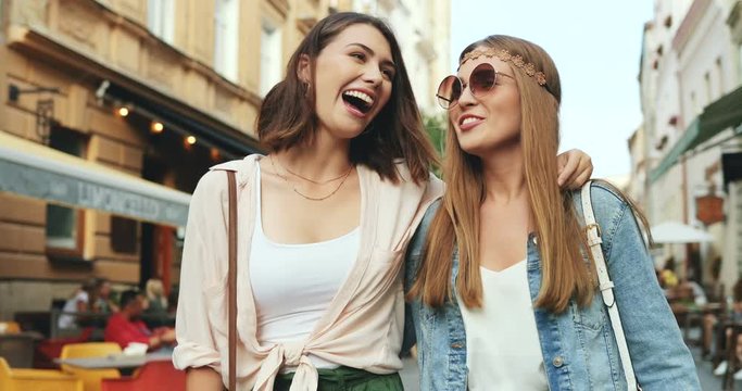Two joyful and beautiful Caucasian young women walking the city together and having fun. Outdoor.