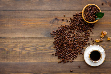 Obraz na płótnie Canvas Brown roasted coffee beans scattered on wooden background and cup of americano top view mockup