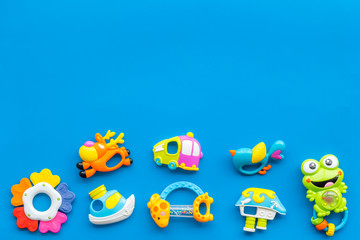 Toys for newborn baby set with plastic rattle on blue background flat lay space for text