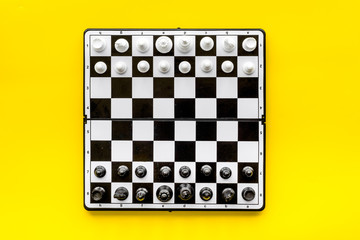 Chess game concept. Chess board with figures on yellow background top view copy space
