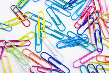 Colored paper clips random on white background, Abstract background, Stationery supplies concepts. Closeup, View from above.