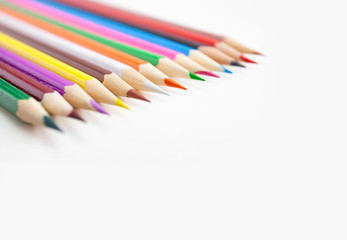 Closeup a row of colored pencils on white background with selective focus with copy space.