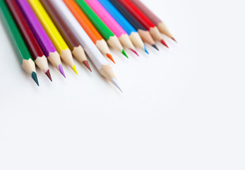 Colorful crayon pencils on white desktop with selected focus on the white color tips with copy space. Top view, closeup.