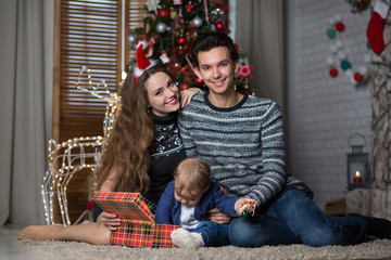 Obraz na płótnie Canvas family sits with the baby sitting near the Christmas tree,