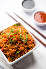 Schezwan Fried Rice Masala is a popular indo-chinese food served in a plate or bowl with chopsticks. selective focus