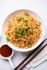 Schezwan Fried Rice Masala is a popular indo-chinese food served in a plate or bowl with chopsticks. selective focus