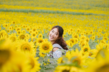 Fototapeta premium Beauty joyful teenage girl with sunflower enjoying nature and laughing on summer sunflower field. 