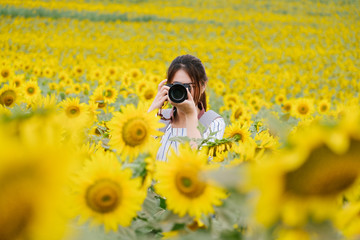 Beauty joyful teenage girl with sunflower enjoying nature and laughing on summer sunflower field. 