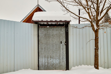 Door in the metal fence in winter day