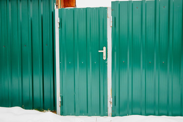 Door in the metal fence in winter day