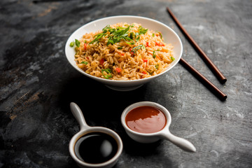 Schezwan Fried Rice Masala is a popular indo-chinese food served in a plate or bowl with chopsticks. selective focus