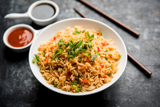 Schezwan Fried Rice Masala is a popular indo-chinese food served in a plate or bowl with chopsticks. selective focus