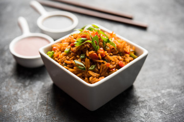 Schezwan Fried Rice Masala is a popular indo-chinese food served in a plate or bowl with chopsticks. selective focus