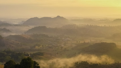 sunrise at Doi Mae Salong, beautiful mountains with green forest around with soft mist and yellow sun light in the sky background, Doi Mae Salong View Point, Chiang Rai, northern Thailand.
