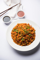 Schezwan Fried Rice Masala is a popular indo-chinese food served in a plate or bowl with chopsticks. selective focus