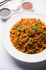 Schezwan Fried Rice Masala is a popular indo-chinese food served in a plate or bowl with chopsticks. selective focus