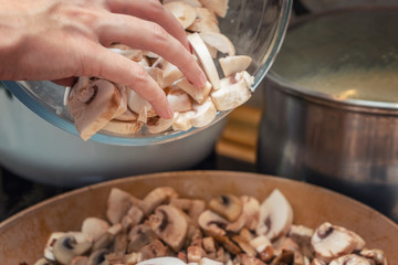 Hands girl cooks pour mushrooms into the pan