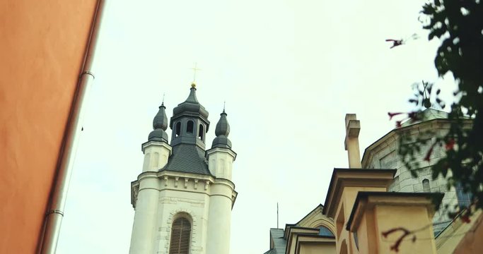View from the arch on the beautiful architecture of the city: tall bell tower of the church. Outside.