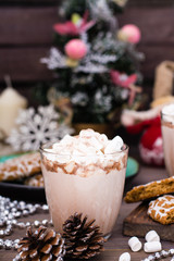 Hot cocoa with marshmallows and cinnamon in glass on the table in Christmas decorations